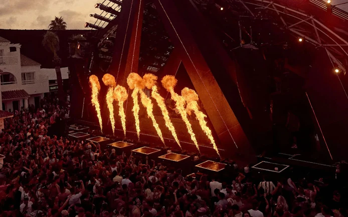 Fire display during Ants Ushuaïa performance in Ibiza with crowd watching.