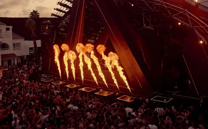 Fire display during Ants Ushuaïa performance in Ibiza with crowd watching.