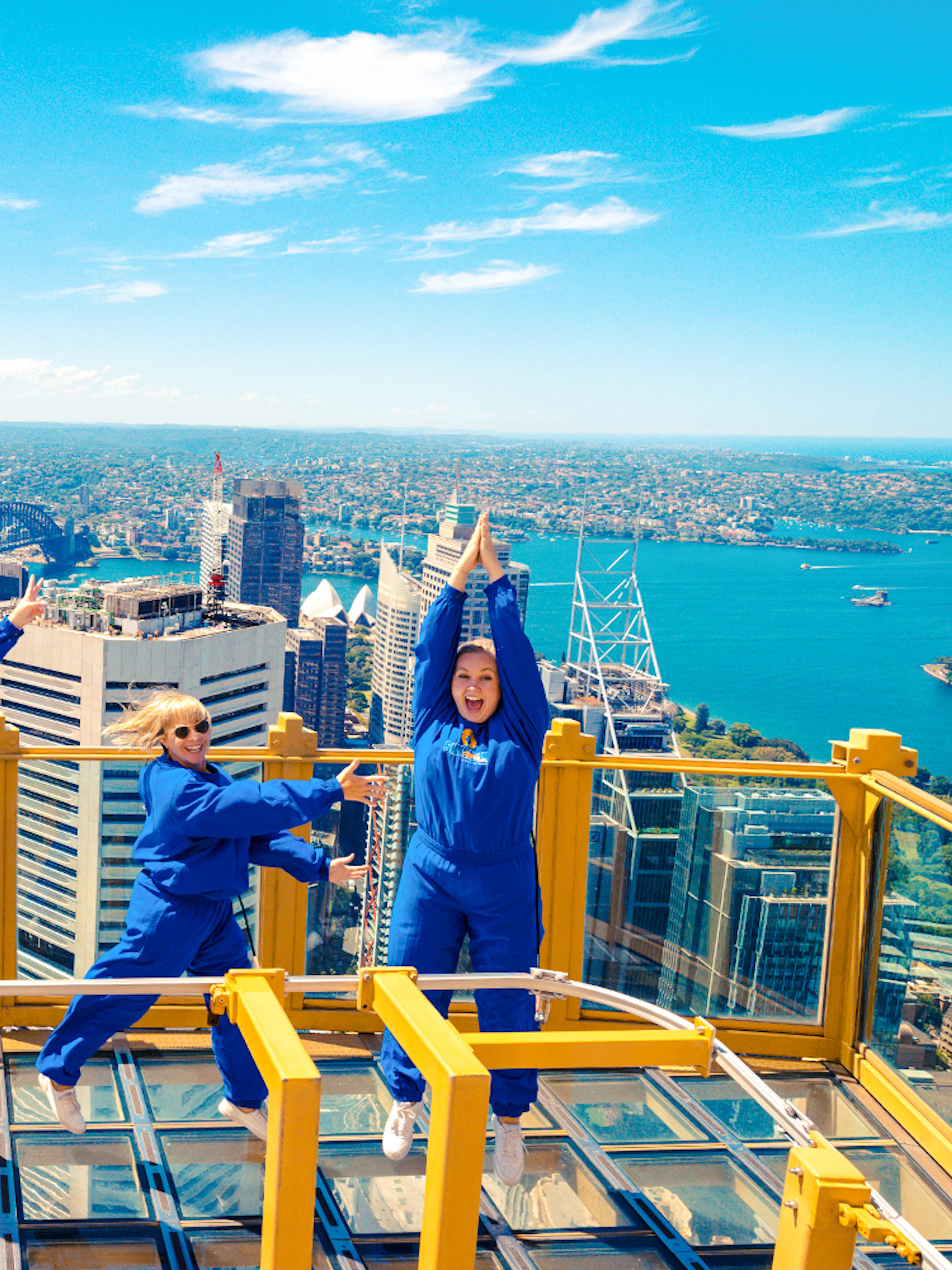 Group enjoying the view from Sydney Tower Eye Skywalk with cityscape and harbor in background.