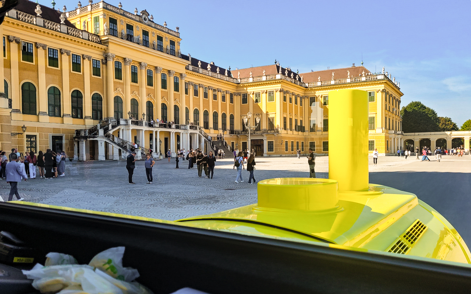 Panorama Train view of Schönbrunn Palace courtyard, Vienna, with visitors exploring.