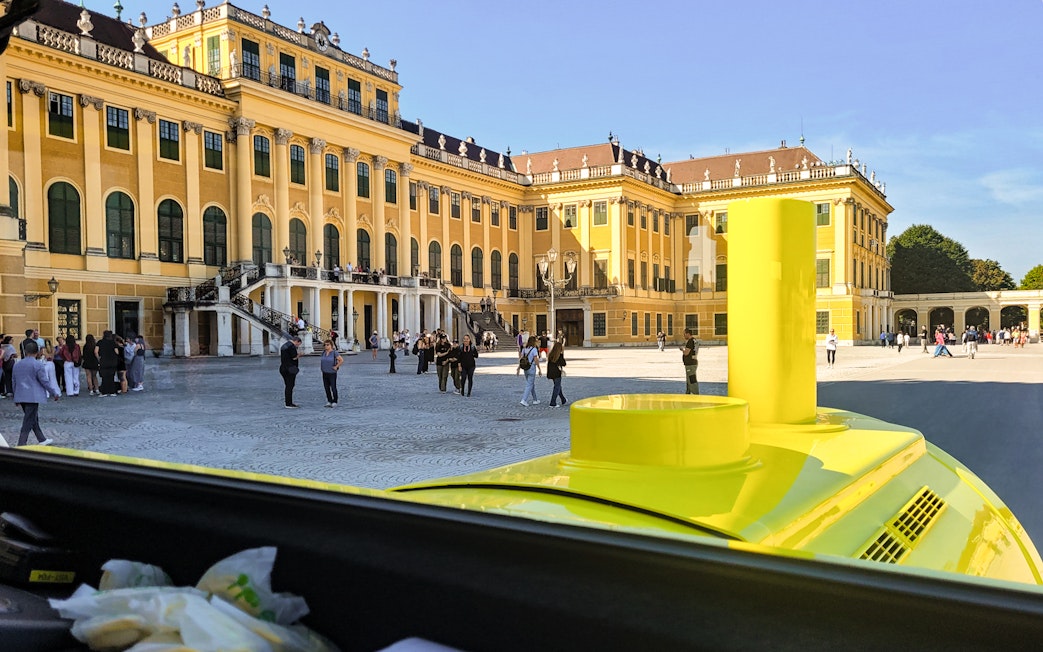 Panorama Train view of Schönbrunn Palace courtyard, Vienna, with visitors exploring.