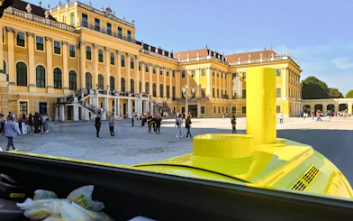 Panorama Train view of Schönbrunn Palace courtyard, Vienna, with visitors exploring.