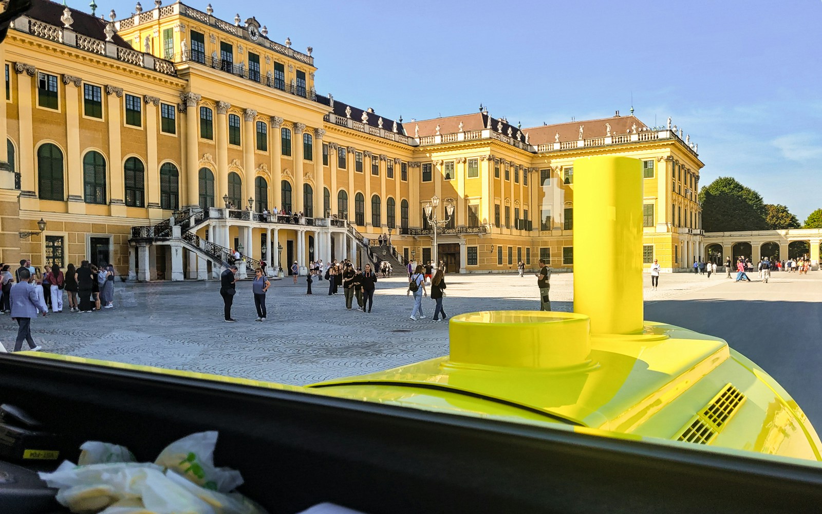 Panorama Train view of Schönbrunn Palace courtyard, Vienna, with visitors exploring.