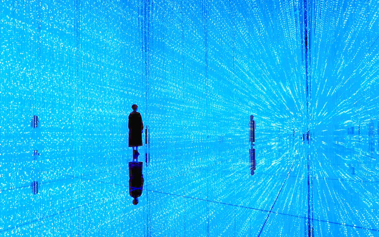 Visitor in illuminated digital art installation at teamLab SuperNature Macau.