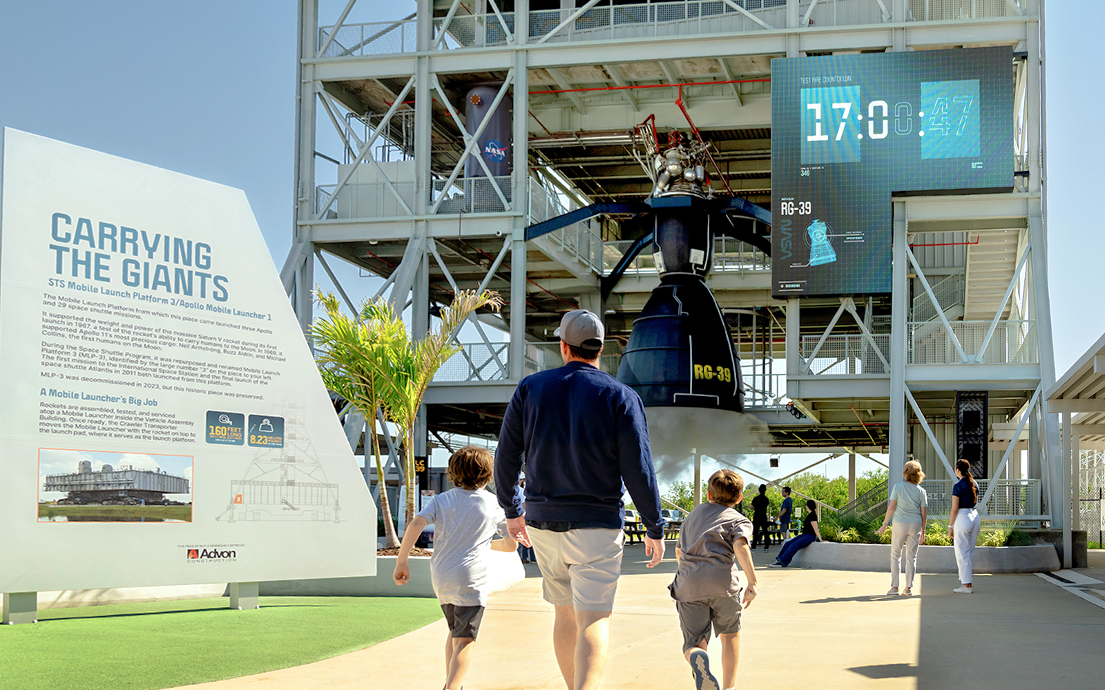 Family exploring Gantry at LC-39, Kennedy Space Center, with countdown display.