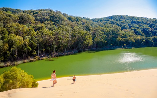 Visitors descending sand dune towards Lake Wabby on Fraser Island, K'gari.