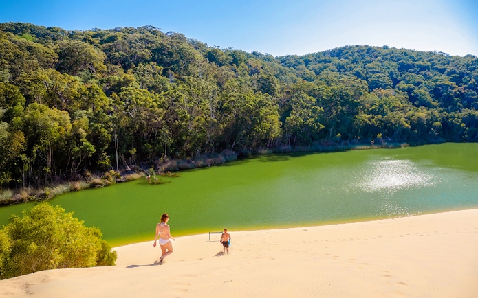 Visitors descending sand dune towards Lake Wabby on Fraser Island, K'gari.