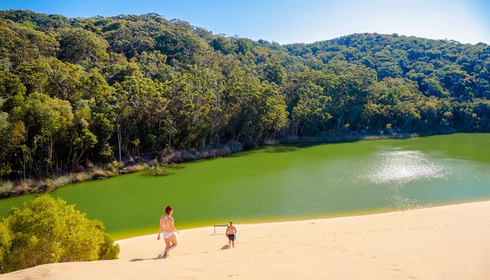 Visitors descending sand dune towards Lake Wabby on Fraser Island, K'gari.