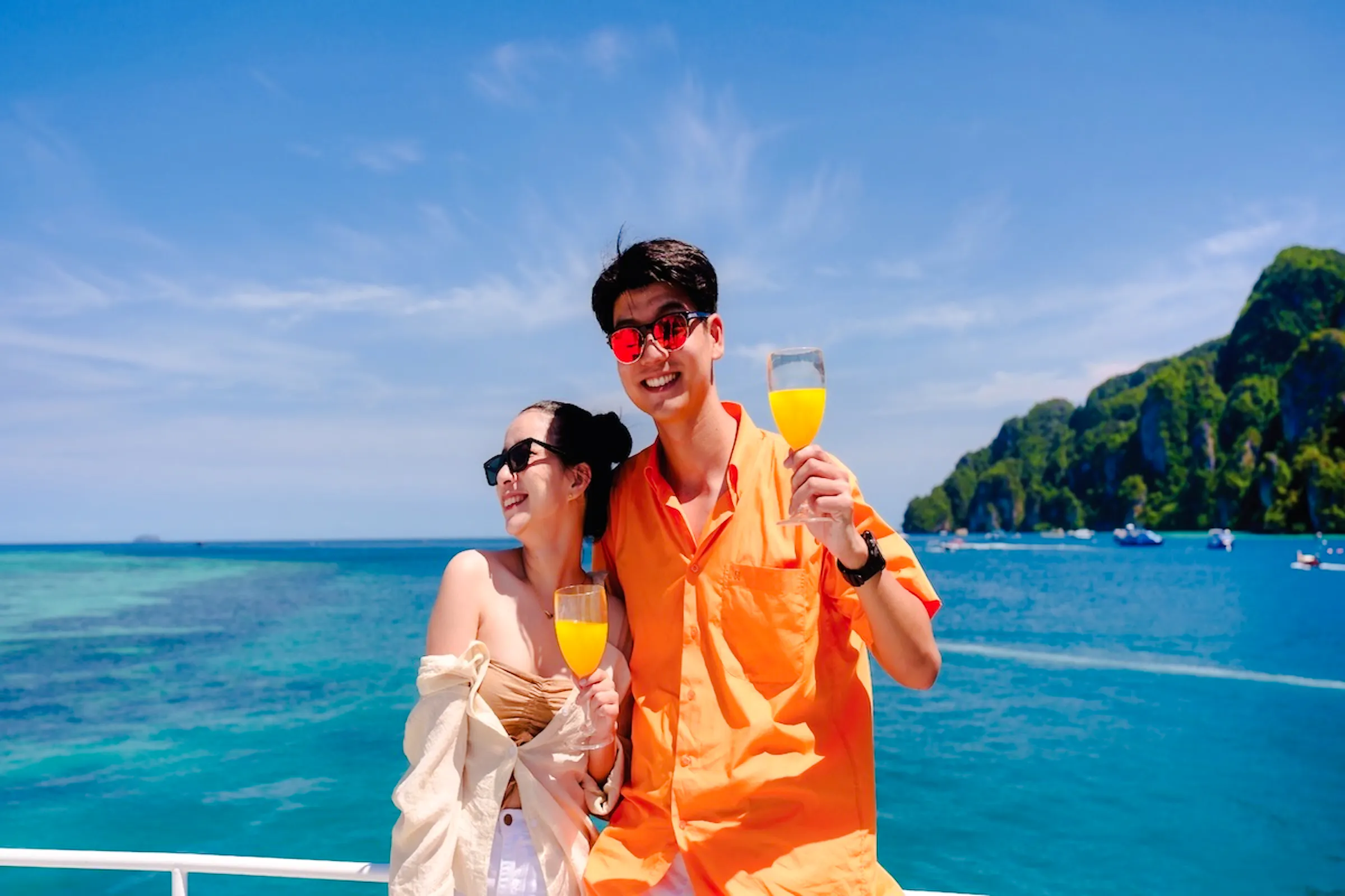 Couple enjoying drinks on a ferry with Phi Phi Islands in the background, Phuket.