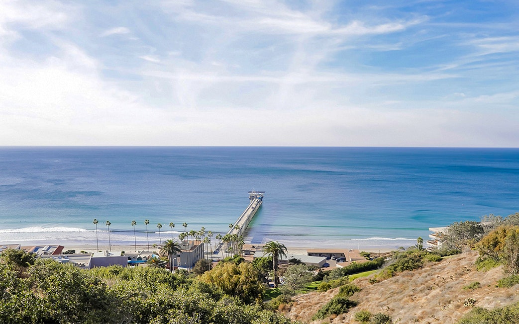 San Diego coastline with pier extending into the ocean, view from hillside.