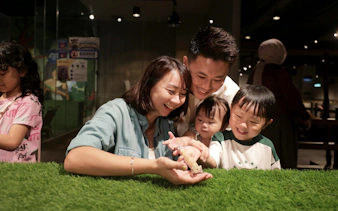 Family interacting with a lizard at Just Farm Indoor Zoo Kuala Lumpur.