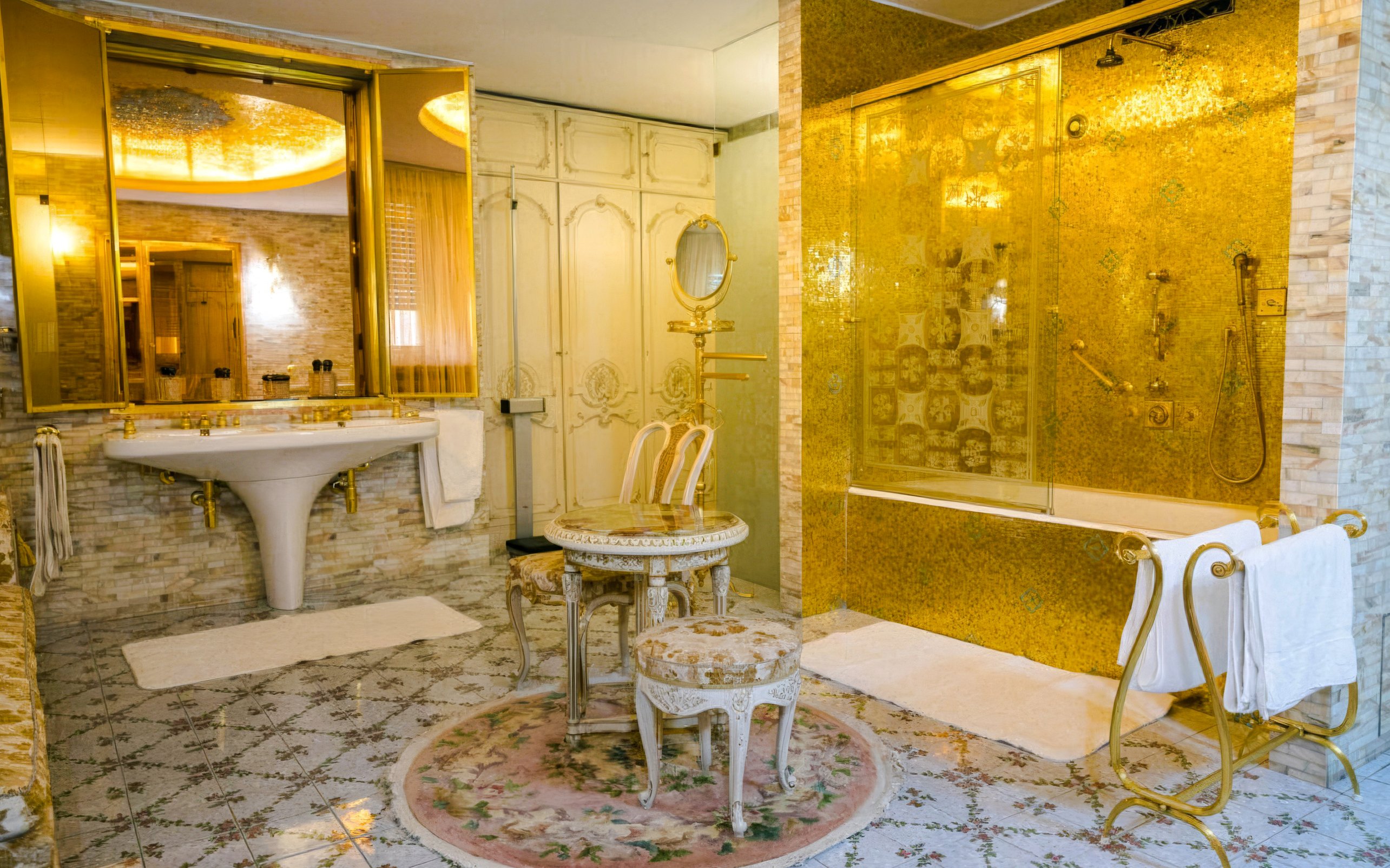 Luxurious bathroom with gold accents inside Ceausescu Mansion, featuring ornate sink and shower.