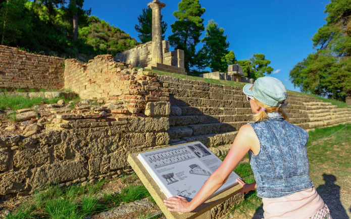 Tourist reading information at Ancient Olympia archaeological site, Greece.