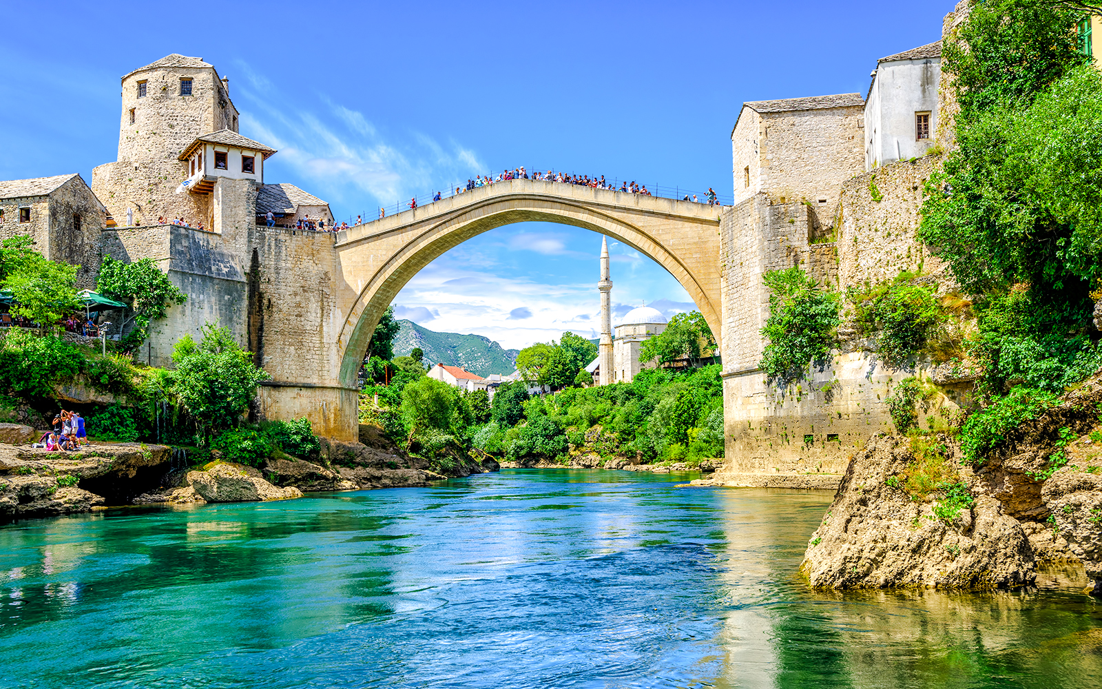 Old Bridge and mosque in Mostar's Old Town, Bosnia, over a turquoise river.