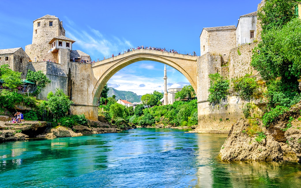Old Bridge and mosque in Mostar's Old Town, Bosnia, over a turquoise river.