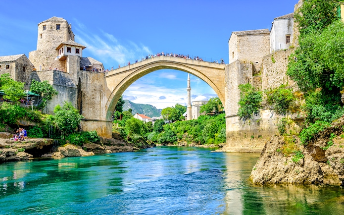 Old Bridge and mosque in Mostar's Old Town, Bosnia, over a turquoise river.
