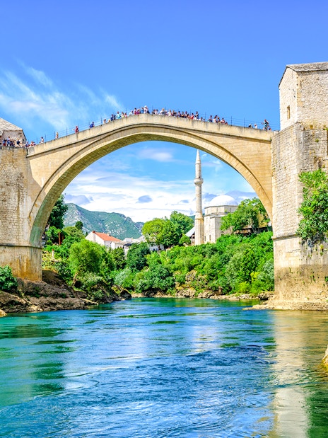 Old Bridge and mosque in Mostar's Old Town, Bosnia, over a turquoise river.
