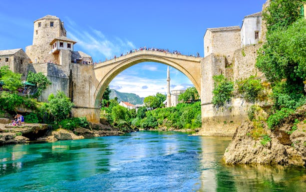 Old Bridge and mosque in Mostar's Old Town, Bosnia, over a turquoise river.