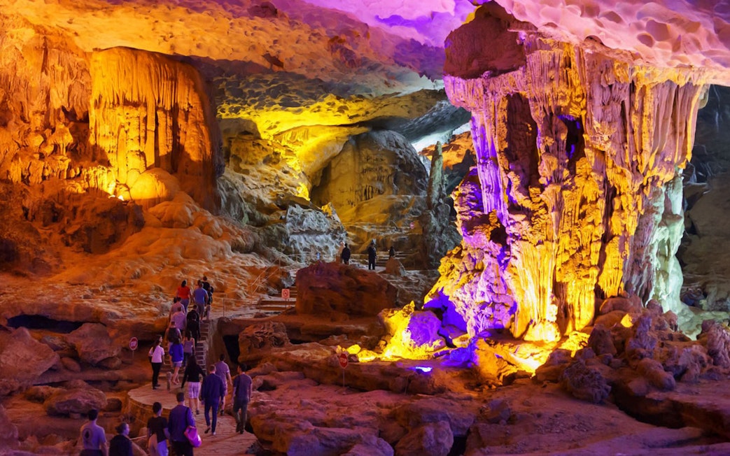 Tourists exploring illuminated cave formations on Ha Long Bay 5-Star Cruise.