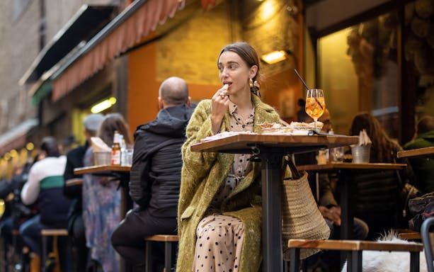 Outdoor dining in Rome with a woman enjoying Italian food and wine.