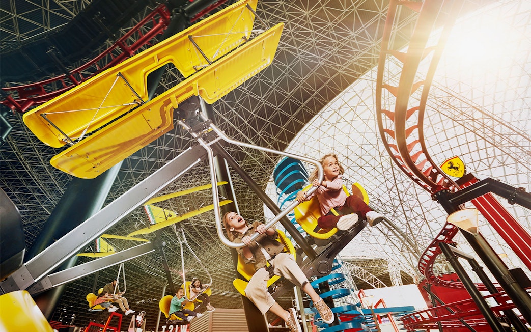 Visitors enjoying a ride at Ferrari World Abu Dhabi under the iconic roof structure.