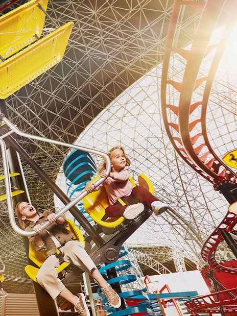 Visitors enjoying a ride at Ferrari World Abu Dhabi under the iconic roof structure.