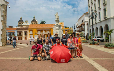 Tour group in Cartagena's historic walled city with guide and red umbrella.