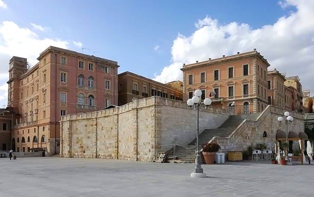 Cagliari Castle district with historic buildings and stone steps under a blue sky.