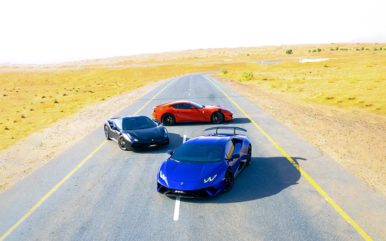 Ferrari and other sports cars on a desert road.