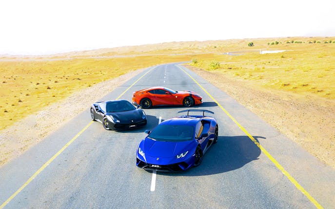 Ferrari and other sports cars on a desert road.