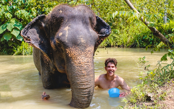 Elephant and person bathing in a river at Ao Nang Elephant Sanctuary.