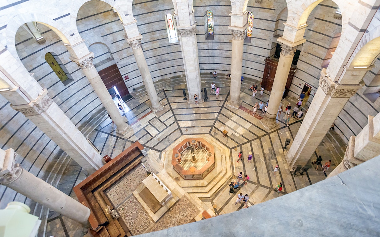 Circular interior of St. John's Baptistery in Pisa with columns and mosaic floor.