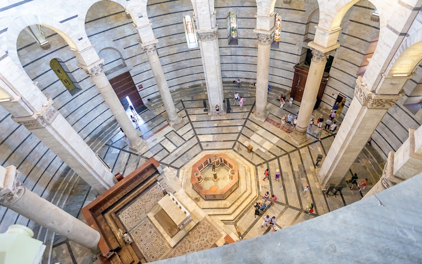 Circular interior of St. John's Baptistery in Pisa with columns and mosaic floor.