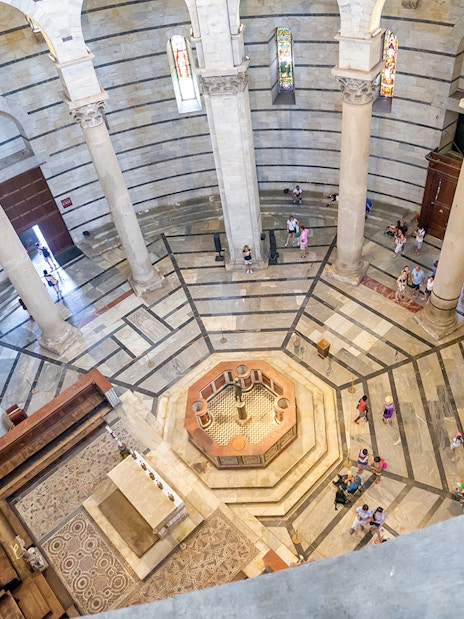 Circular interior of St. John's Baptistery in Pisa with columns and mosaic floor.