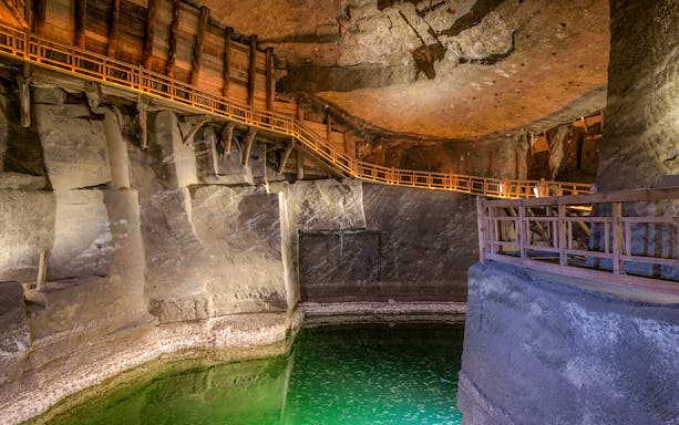 Wieliczka Salt Mine chamber with wooden walkways and illuminated salt formations, Krakow tour.