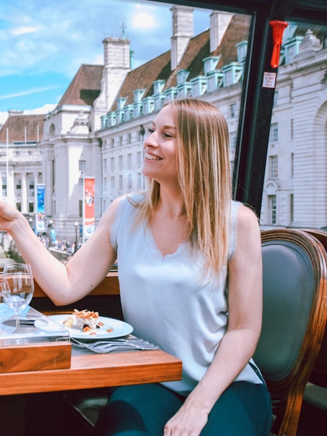 Two people toasting with wine on the Bustronome London tour, with the London Eye in the background.