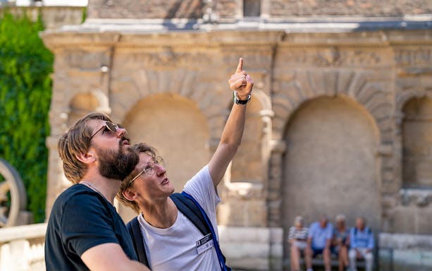 Tour guide pointing out historical architecture in the Marais, Paris.