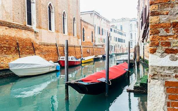 Venice canal with moored boats and historic brick buildings.