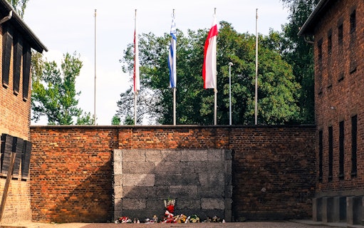 Execution wall at Auschwitz-Birkenau with memorial flowers, part of guided tour from Warsaw.