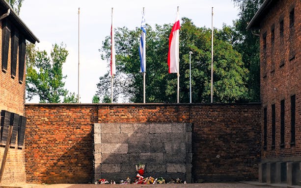 Execution wall at Auschwitz-Birkenau with memorial flowers, part of guided tour from Warsaw.