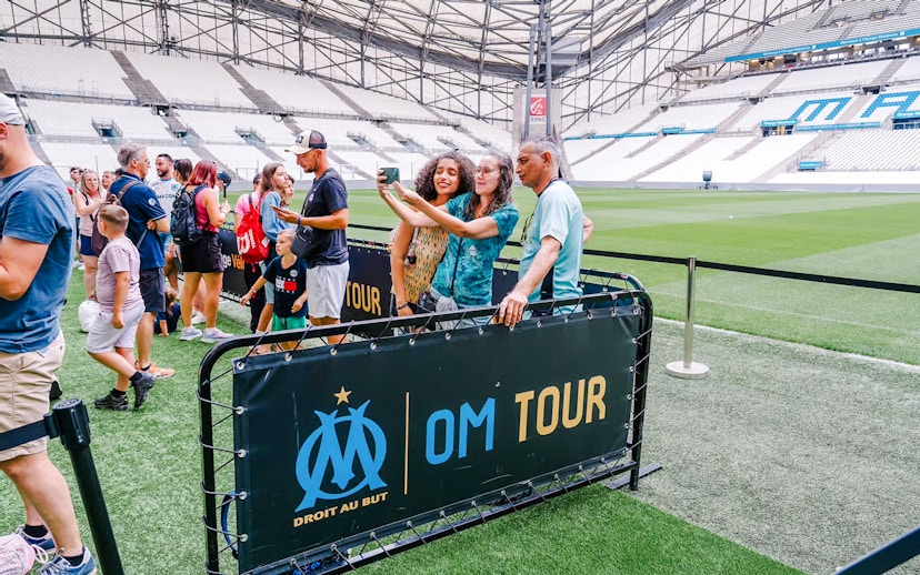 Visitors taking a selfie during a Velodrome stadium tour in Marseille.