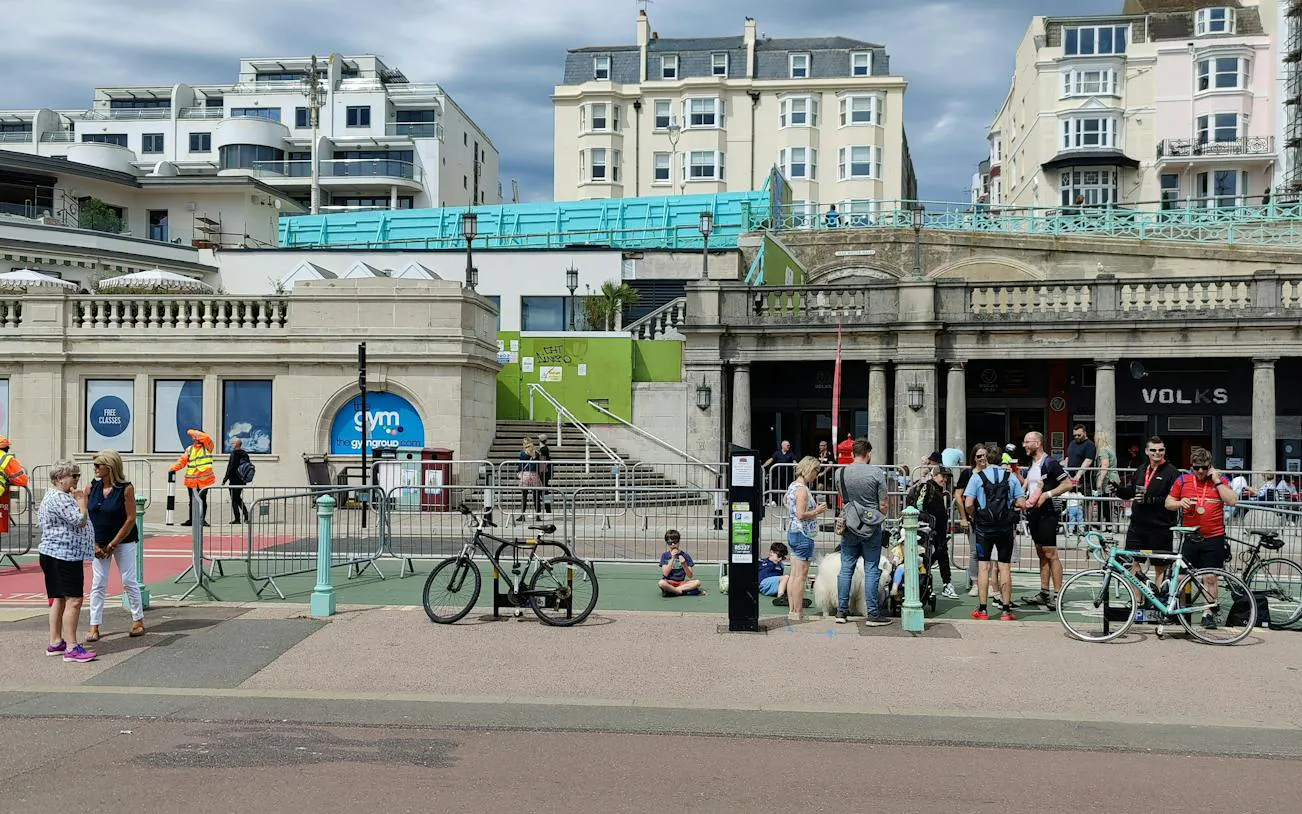 Brighton seafront with people gathered near historic arches, part of a self-guided city exploration game.