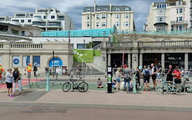 Brighton seafront with people gathered near historic arches, part of a self-guided city exploration game.