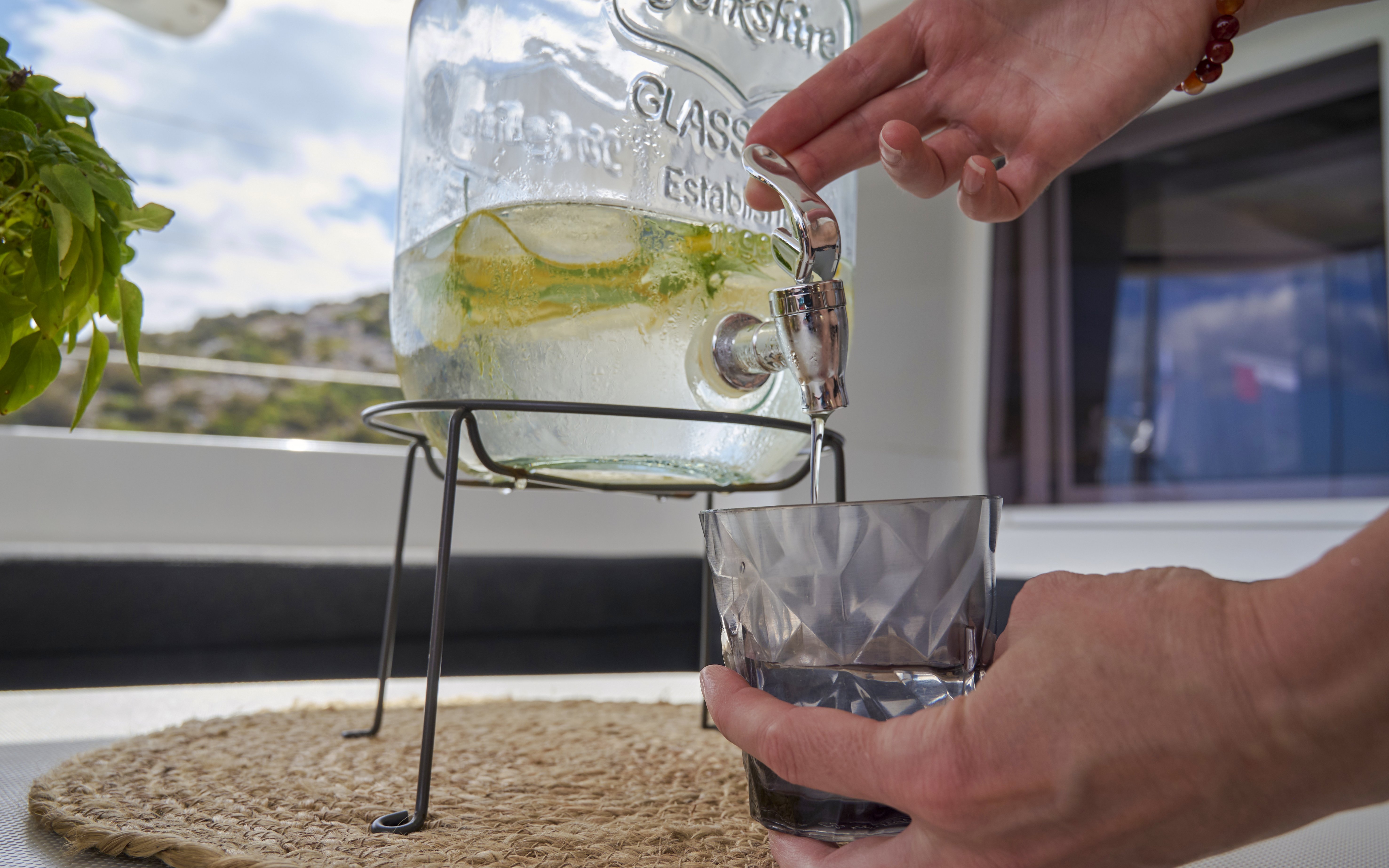 Pouring a drink from a dispenser on a catamaran cruise near Spinalonga, Crete.