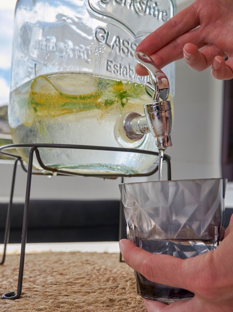 Pouring a drink from a dispenser on a catamaran cruise near Spinalonga, Crete.