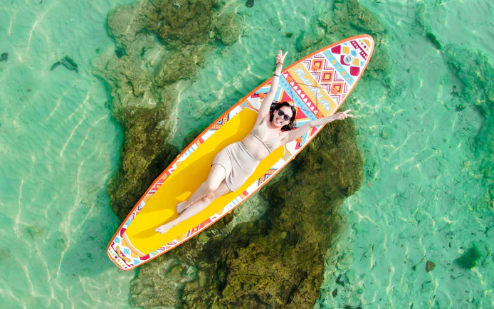 Tourist relaxing on paddle board in clear waters at 4 Islands tour, Vietnam.