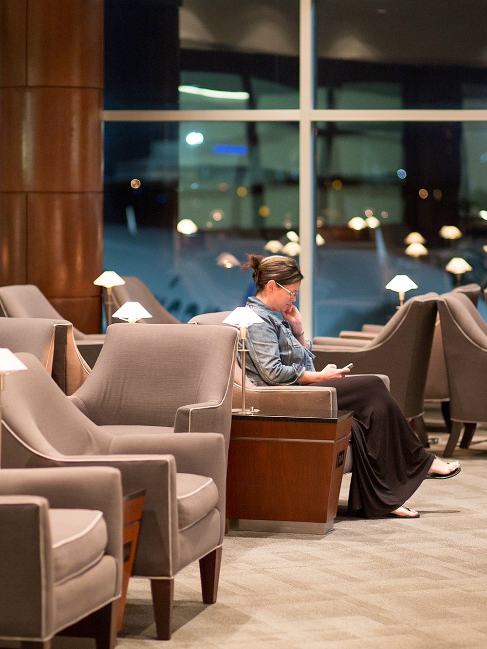 Woman reading in airport lounge with empty seats around.