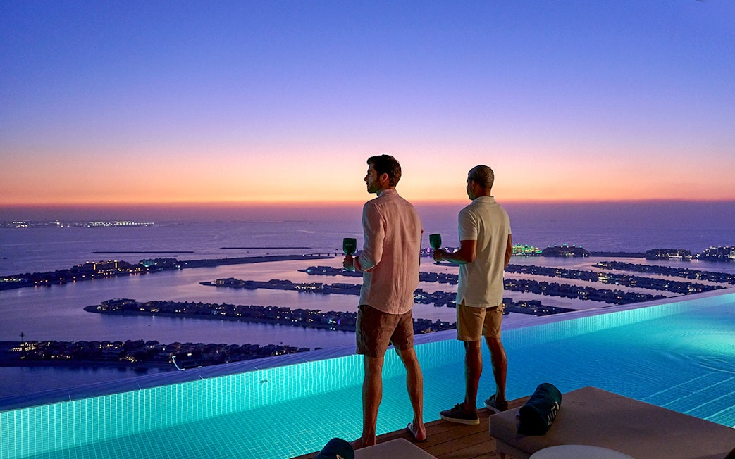 Tourists enjoying sunset view of Palm Jumeirah from Aura Sky Pool, Dubai.