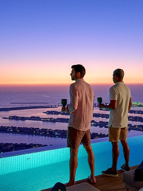 Tourists enjoying sunset view of Palm Jumeirah from Aura Sky Pool, Dubai.