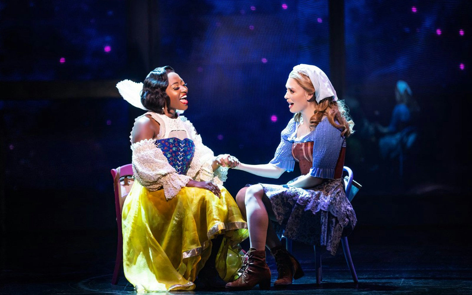 Two performers in costume holding hands on stage during "Once Upon a One More Time" musical.